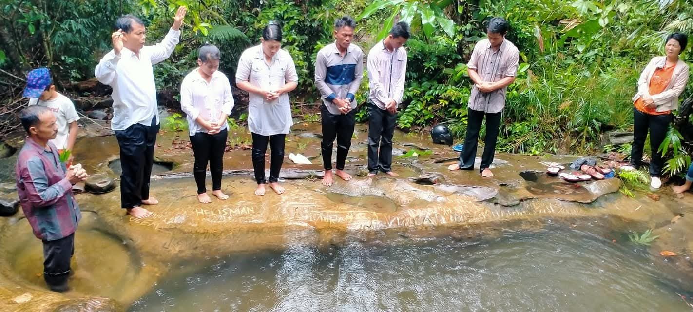 Peserta baptisan air berdoa bersama gembala sidang di sungai