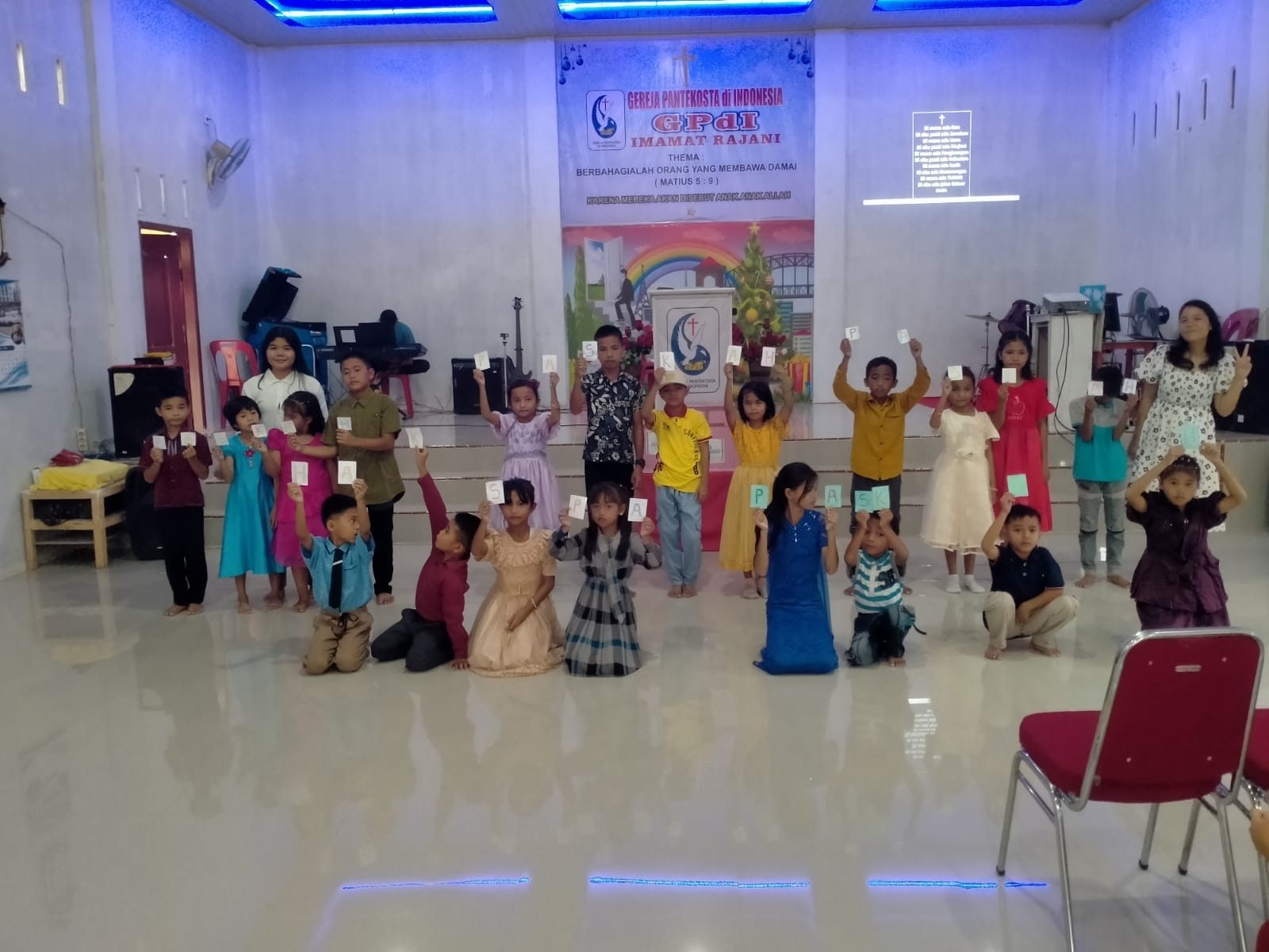 Anak-anak Sekolah Minggu mengangkat kartu bertuliskan Selamat Paskah