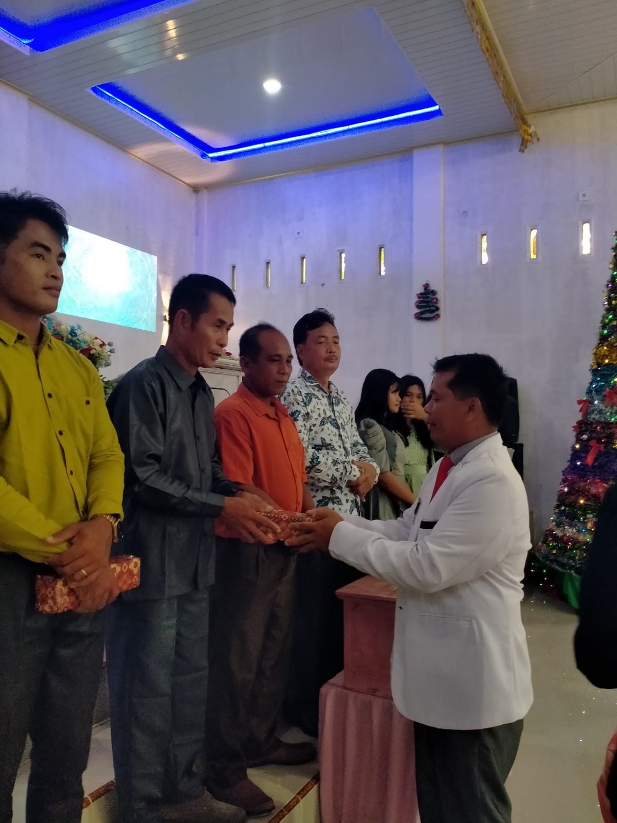 Gembala sidang menyerahkan bingkisan kepada jemaat pada ibadah Natal